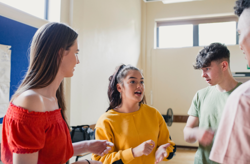 Four teenagers smiling at one another