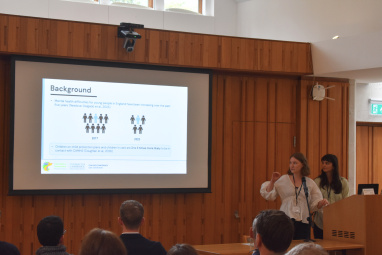 Two women presenting at an event in front of a screen