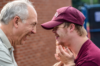 A young person and his grandpa smiling at each other.