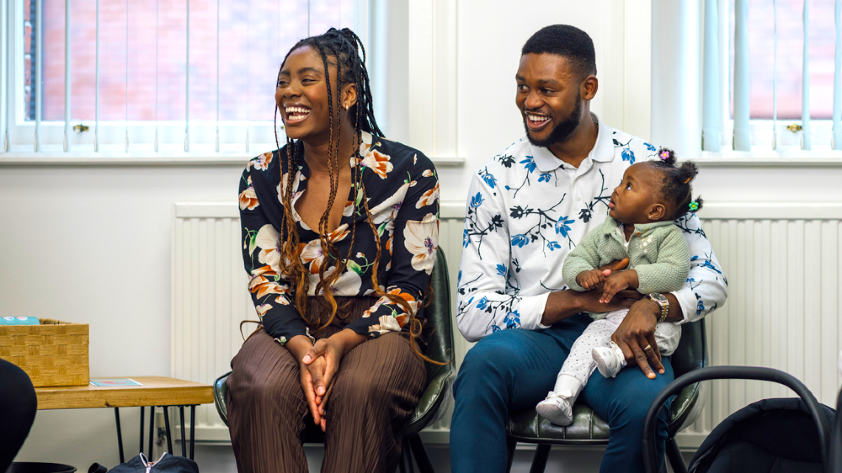 Parents with baby sitting in a waiting room, smiling