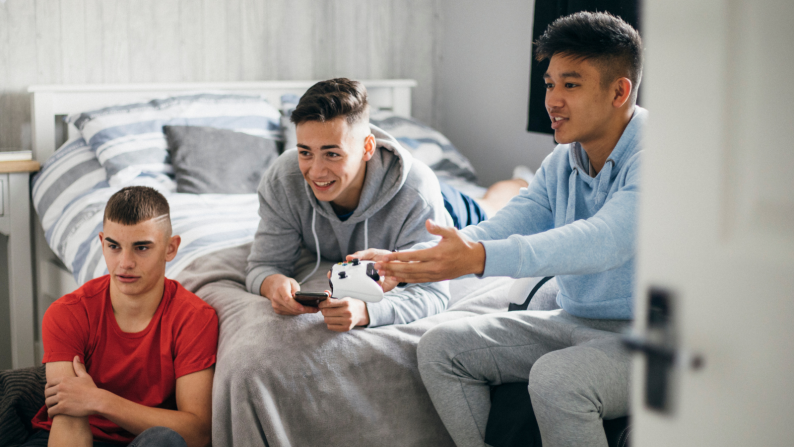 Three boys playing a games console
