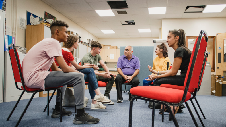 Group of young people sat on chairs in a circle