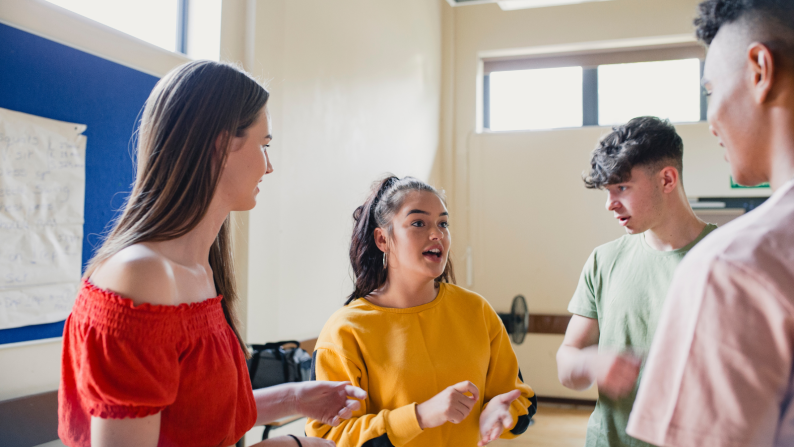 Four teenagers smiling at one another