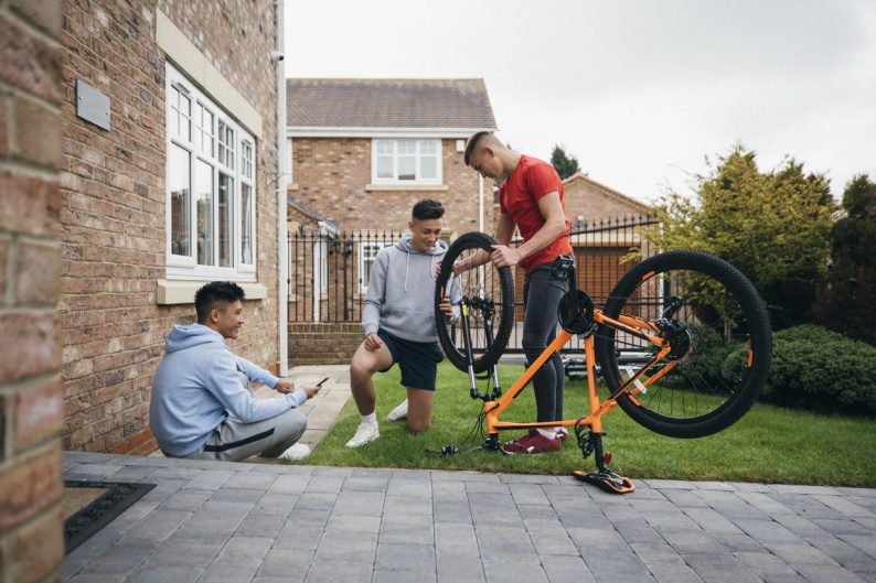 Teenage boys in a garden fixing a bike