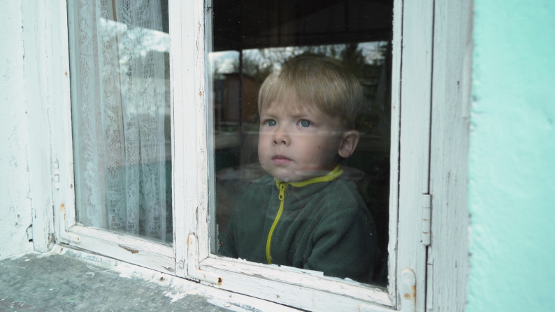 Young boy looking pensively out of a window