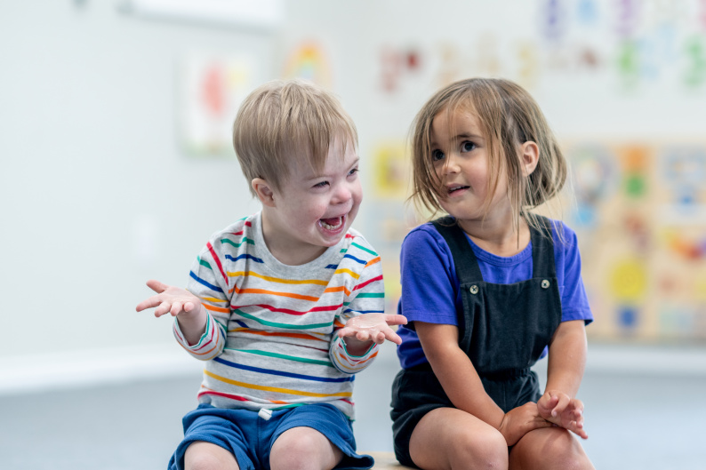 A boy and girl sat together in an early education setting