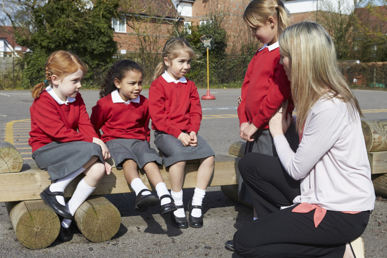 Image of pupils in a playground with a teacher