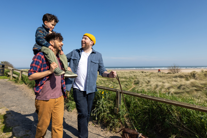 Two men laughing with child on one man's shoulders
