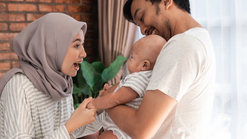 Image of woman smiling at a baby who is being held by a man affectionately
